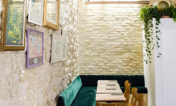 Coffee shop à Paris avec décoration composée de marbre rose, banquette en velours vert, dessins Love signés Yves Saint Laurent