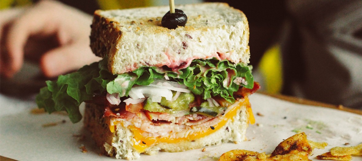 Sandwich with bread, salad, cheddar, tomatoes, onions, pickle, ham from Club Sandwich