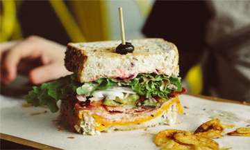 Sandwich with bread, salad, cheddar, tomatoes, onions, pickle, ham from Club Sandwich