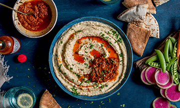 Houmous a l'harissa avec de la sauce Tabasco rouge et comme accompagnements des legumes et du pain