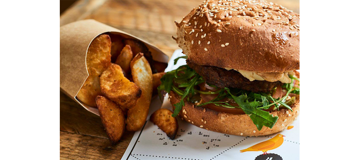 Plat de burger avec oignons, cornichon, pousse de graine germées et feuille de chêne et Frites