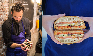 Le chef Yoni Saada tenant des olives et un Sandwich légumes au piment fumé, taboulé d’herbes fraîches, raisins blonds, tomates confites