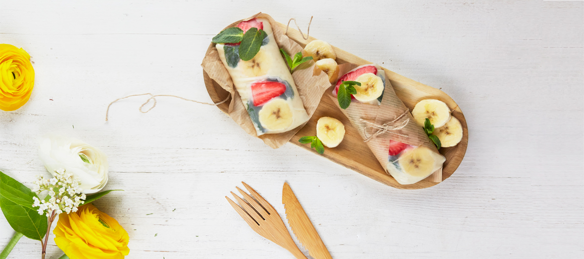 Rouleaux de printemps avec banane, galette de riz, du lait entier, des fraises et des feuilles de menthe 