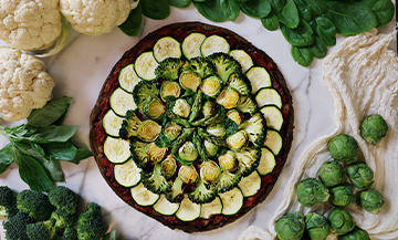 Low calorie pizza with cauliflower, broccoli, zucchini, asparagus, goat cheese, egg, spirulina, minced basil, tomato puree