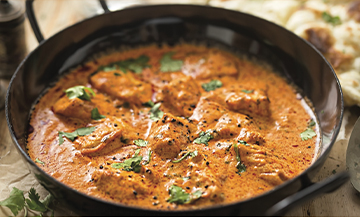 Plat de chicken butter avec poulet, ail, gingembre, oignons, noix de cajou, feuilles de coriandre, tomate, cumin en poudre, poudre de piment 