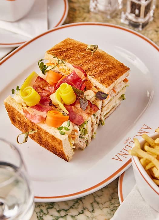 Club sandwich gourmand de la maison Angelina à Paris, servi avec légumes et bacon croustillant.