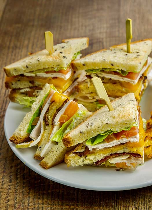 Club sandwich généreux du Coffee Club à Paris, garni de poulet, salade et fromage.