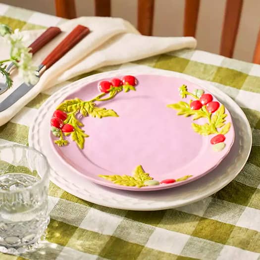 Assiette rose décorée de tomates cerises en relief, posée sur une table à carreaux verts pour un tea time printanier