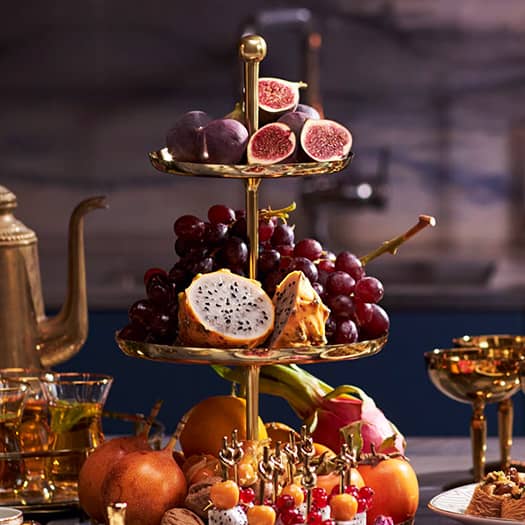 Présentoir doré à étages garni de fruits frais pour un tea time élégant et coloré