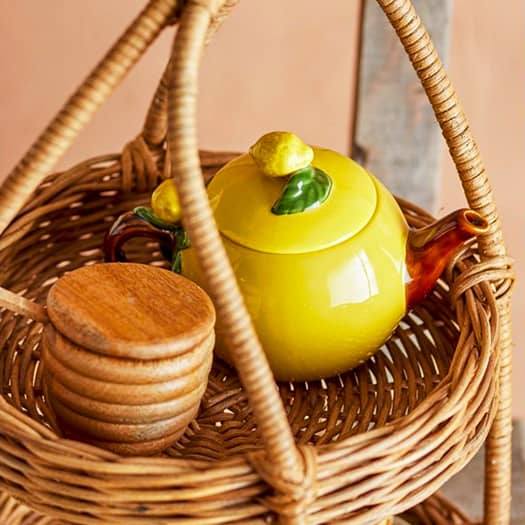 Théière en céramique jaune citron sur un panier en osier, ambiance rustique et chaleureuse