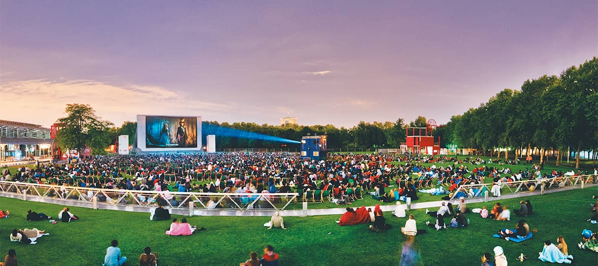 Grand écran de cinéma en plein air à La Villette, avec public allongé sur la pelouse pour une séance d’été.