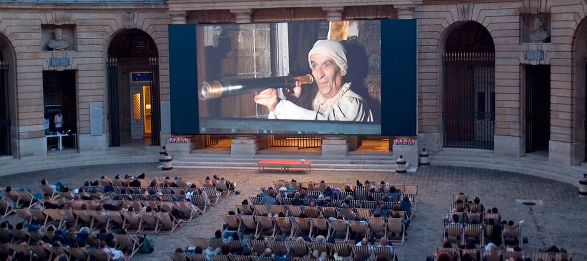 Projection de film dans la cour de la Monnaie de Paris, ambiance classique et estivale sous les arcades.
