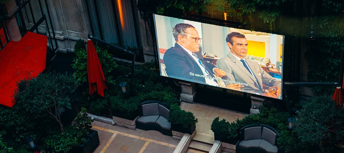 Écran de cinéma en rooftop sur jardin avec transats au Plaza Athénée, vue panoramique sur Paris.