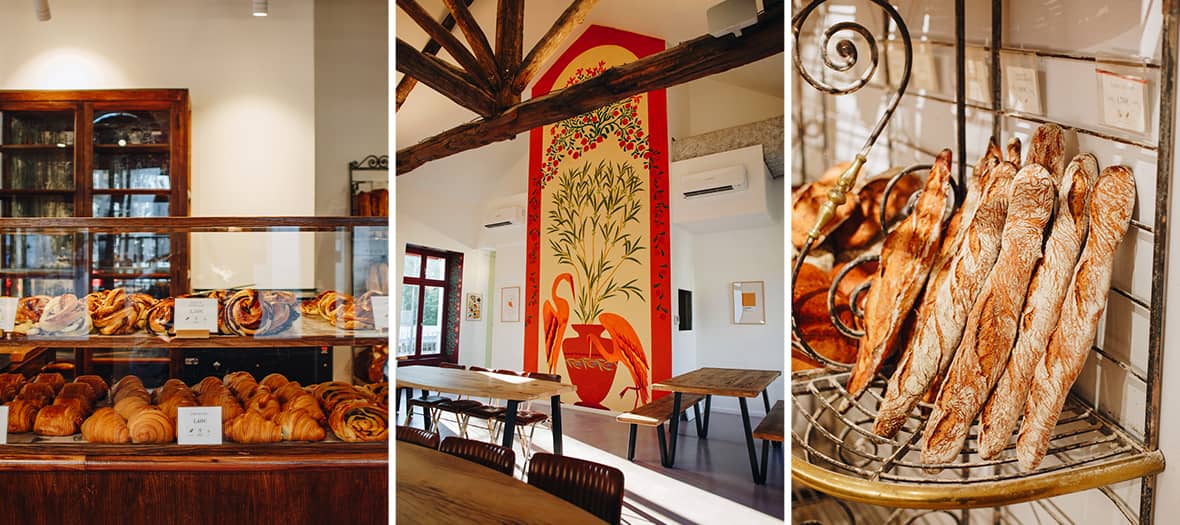 Int&eacute;rieur de la Boulangerie Leonie Reuilly &agrave; Paris avec vitrine en bois remplie de croissants et brioches, grande fresque murale color&eacute;e et pr&eacute;sentoir de baguettes traditionnelles croustillantes. 